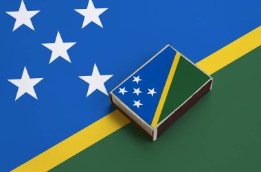 Solomon Adaları bayrağı üzerinde büyük bir bayrak yatıyor bir kibrit kutusu üzerinde resimde.