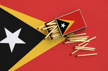 Timor Leste bayrak bir kibrit kutusu içinden birkaç sonbahar eşleşir ve büyük bir bayrak üzerinde yatıyor açık gösterilir.