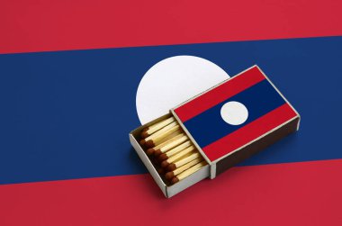 Laos bayrağı açık bir kibrit kutusu içinde gösterilen hangi dolu maçlar ve büyük bir bayrak üzerinde yatıyor.