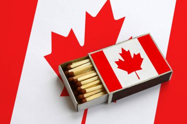 Kanada bayrağı açık bir kibrit kutusu içinde gösterilen hangi dolu maçlar ve büyük bir bayrak üzerinde yatıyor.