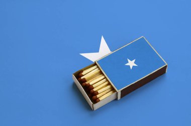 Somali bayrağı açık bir kibrit kutusu içinde gösterilen hangi dolu maçlar ve büyük bir bayrak üzerinde yatıyor.