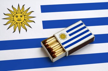 Uruguay bayrağı açık bir kibrit kutusu içinde gösterilen hangi dolu maçlar ve büyük bir bayrak üzerinde yatıyor.