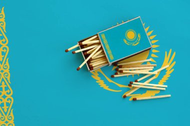 Kazakistan bayrağı bir kibrit kutusu içinden birkaç sonbahar eşleşir ve büyük bir bayrak üzerinde yatıyor açık gösterilir.