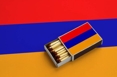 Ermenistan bayrağı açık bir kibrit kutusu içinde gösterilen hangi dolu maçlar ve büyük bir bayrak üzerinde yatıyor.