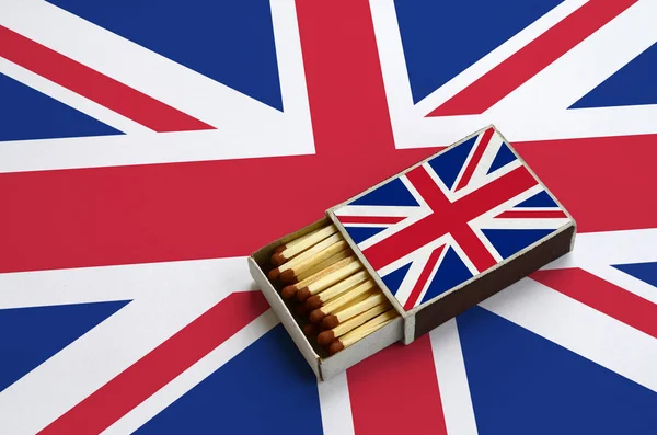 Great britain flag  is shown in an open matchbox, which is filled with matches and lies on a large flag.