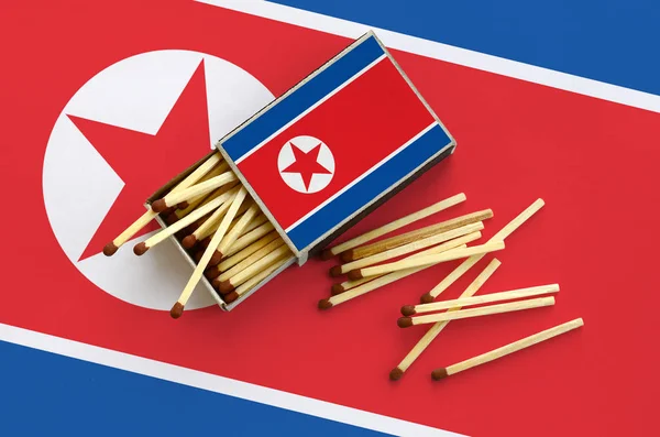北朝鲜旗子在一个打开的火柴盒显示 几个比赛下落和说谎在一个大旗子 — 图库照片