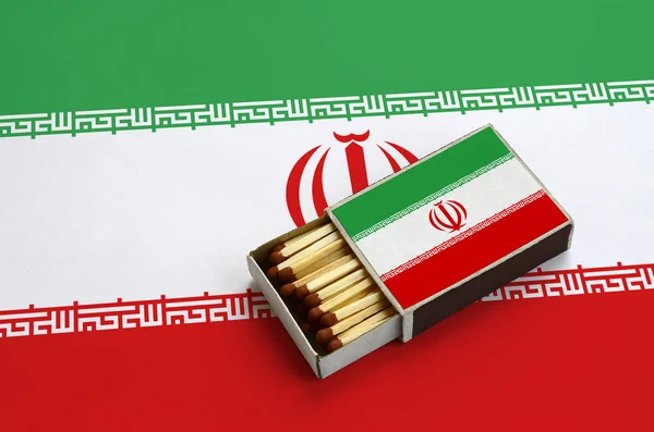 Iran bayrağı açık bir kibrit kutusu içinde gösterilen hangi dolu maçlar ve büyük bir bayrak üzerinde yatıyor.