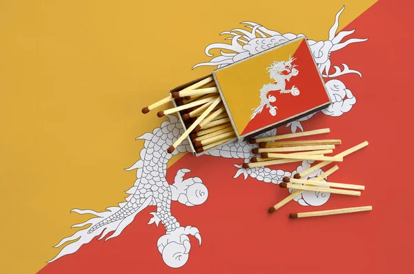 Bhutan bayrağı bir kibrit kutusu içinden birkaç sonbahar eşleşir ve büyük bir bayrak üzerinde yatıyor açık gösterilir.