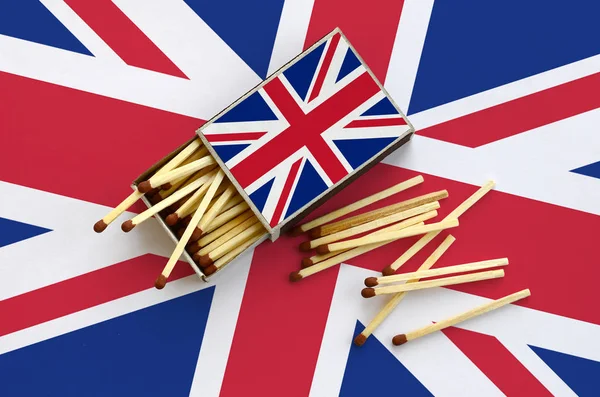 Great britain flag  is shown on an open matchbox, from which several matches fall and lies on a large flag.