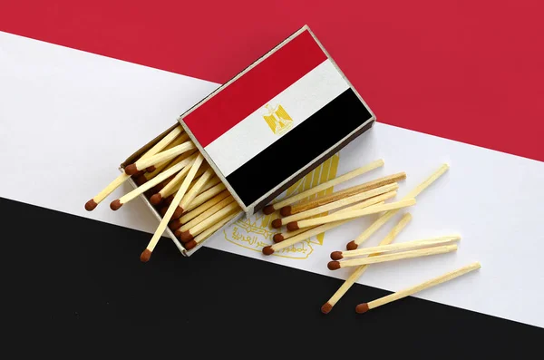 Egypt flag  is shown on an open matchbox, from which several matches fall and lies on a large flag.