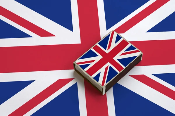 Great britain flag  is pictured on a matchbox that lies on a large flag.