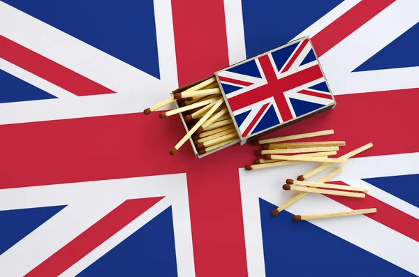 Büyük Britanya bayrağı bir kibrit kutusu içinden birkaç sonbahar eşleşir ve büyük bir bayrak üzerinde yatıyor açık gösterilir.