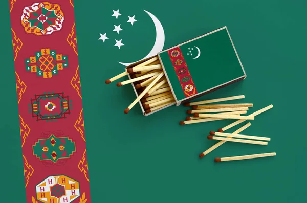 Türkmenistan bayrağı bir kibrit kutusu içinden birkaç sonbahar eşleşir ve büyük bir bayrak üzerinde yatıyor açık gösterilir.