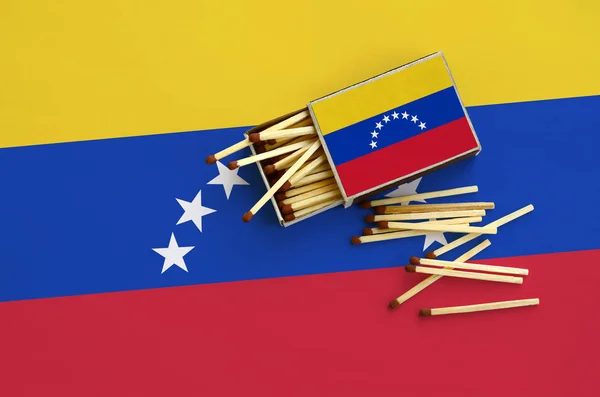 Venezuela flag  is shown on an open matchbox, from which several matches fall and lies on a large flag.