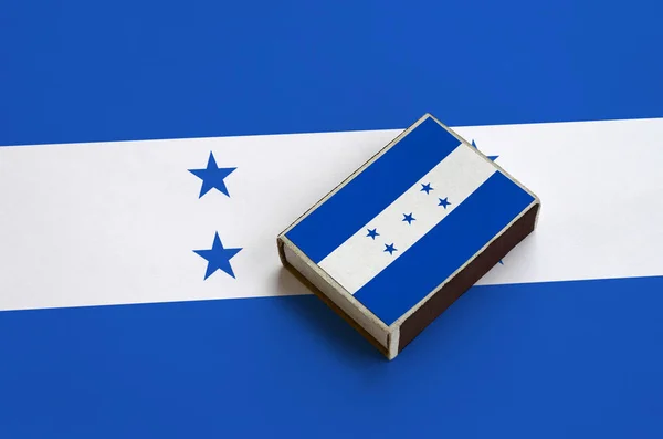 Honduras flag  is pictured on a matchbox that lies on a large flag.