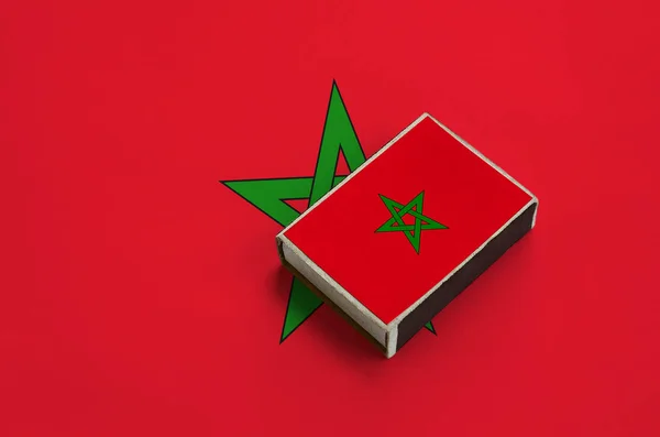 Morocco flag  is pictured on a matchbox that lies on a large flag.