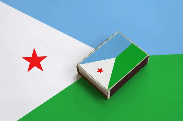 Djibouti flag  is pictured on a matchbox that lies on a large flag.