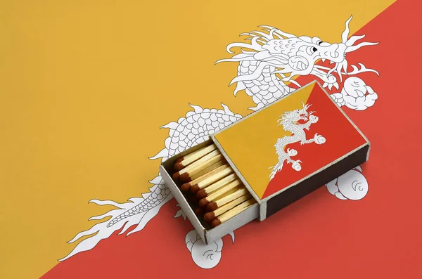 Bhutan bayrağı açık bir kibrit kutusu içinde gösterilen hangi dolu maçlar ve büyük bir bayrak üzerinde yatıyor.
