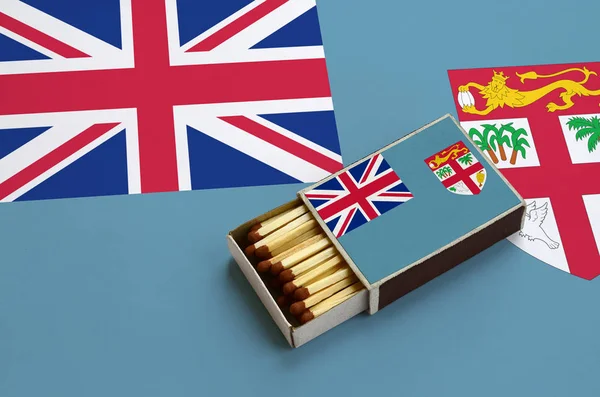 Fiji bayrak açık bir kibrit kutusu içinde gösterilen hangi dolu maçlar ve büyük bir bayrak üzerinde yatıyor.