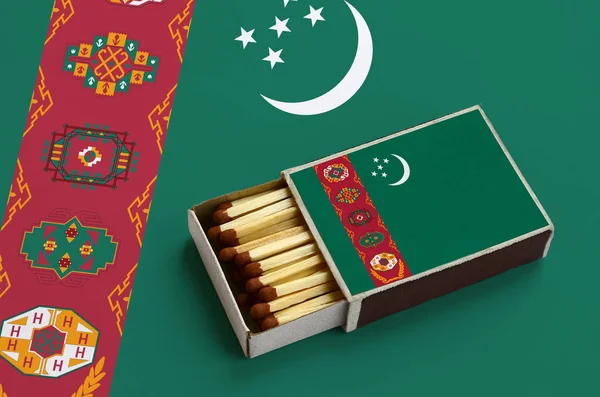 Türkmenistan bayrağı açık bir kibrit kutusu içinde gösterilen hangi dolu maçlar ve büyük bir bayrak üzerinde yatıyor.