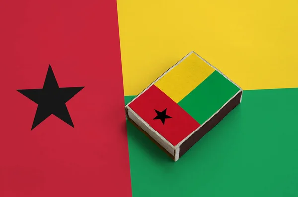 Guinea Bissau flag  is pictured on a matchbox that lies on a large flag.