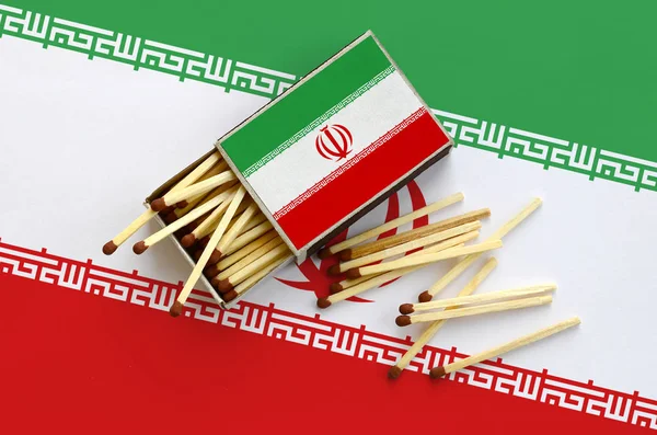 Iran bayrağı bir kibrit kutusu içinden birkaç sonbahar eşleşir ve büyük bir bayrak üzerinde yatıyor açık gösterilir.