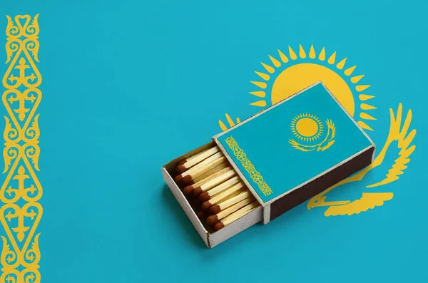 Kazakistan bayrağı açık bir kibrit kutusu içinde gösterilen hangi dolu maçlar ve büyük bir bayrak üzerinde yatıyor.