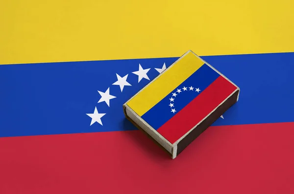 Venezuela flag  is pictured on a matchbox that lies on a large flag.