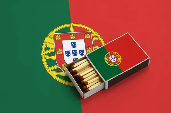Portugal flag  is shown in an open matchbox, which is filled with matches and lies on a large flag.