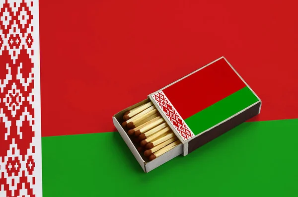 Belarus flag is shown in an open matchbox, which is filled with matches and lies on a large flag. — Stock Image Belarus Flag Shown Open Matchbox Which Filled Matches Lies Large Stock Picture