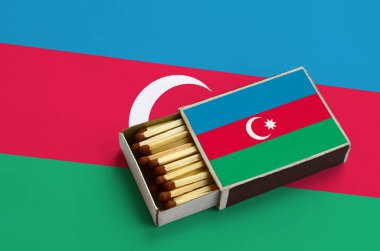 Azerbaycan bayrağı açık bir kibrit kutusu içinde gösterilen hangi dolu maçlar ve büyük bir bayrak üzerinde yatıyor.