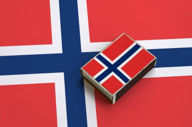 Norveç bayrağı üzerinde büyük bir bayrak yatıyor bir kibrit kutusu üzerinde resimde.