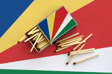 Seyşel Adaları bayrağı bir kibrit kutusu içinden birkaç sonbahar eşleşir ve büyük bir bayrak üzerinde yatıyor açık gösterilir.