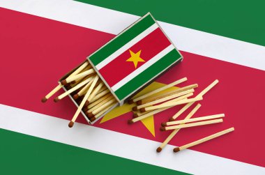 Surinam bayrak bir kibrit kutusu içinden birkaç sonbahar eşleşir ve büyük bir bayrak üzerinde yatıyor açık gösterilir.