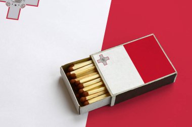 Malta bayrağı açık bir kibrit kutusu içinde gösterilen hangi dolu maçlar ve büyük bir bayrak üzerinde yatıyor.