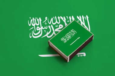 Suudi Arabistan bayrağı üzerinde büyük bir bayrak yatıyor bir kibrit kutusu üzerinde resimde.