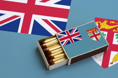 Fiji bayrak açık bir kibrit kutusu içinde gösterilen hangi dolu maçlar ve büyük bir bayrak üzerinde yatıyor.