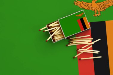 Zambiya bayrağı bir kibrit kutusu içinden birkaç sonbahar eşleşir ve büyük bir bayrak üzerinde yatıyor açık gösterilir.