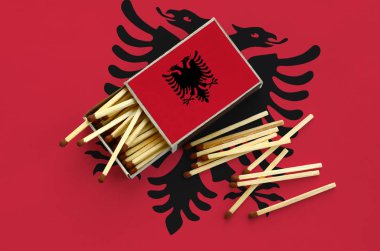  Arnavutluk bayrağı bir kibrit kutusu içinden birkaç sonbahar eşleşir ve büyük bir bayrak üzerinde yatıyor açık gösterilir.