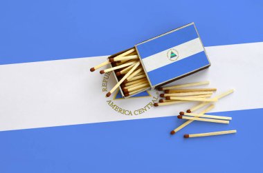 Nikaragua bayrağı bir kibrit kutusu içinden birkaç sonbahar eşleşir ve büyük bir bayrak üzerinde yatıyor açık gösterilir.