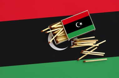Libya bayrağı bir kibrit kutusu içinden birkaç sonbahar eşleşir ve büyük bir bayrak üzerinde yatıyor açık gösterilir.