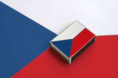 Çek bayrağı üzerinde büyük bir bayrak yatıyor bir kibrit kutusu üzerinde resimde.