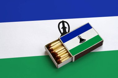 Lesoto bayrağı açık bir kibrit kutusu içinde gösterilen hangi dolu maçlar ve büyük bir bayrak üzerinde yatıyor.