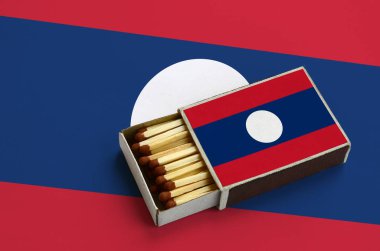 Laos bayrağı açık bir kibrit kutusu içinde gösterilen hangi dolu maçlar ve büyük bir bayrak üzerinde yatıyor.