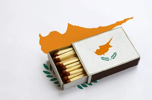 Cyprus flag  is shown in an open matchbox, which is filled with matches and lies on a large flag.