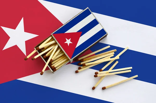 Küba bayrağı bir kibrit kutusu içinden birkaç sonbahar eşleşir ve büyük bir bayrak üzerinde yatıyor açık gösterilir.