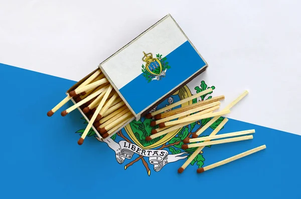 San Marino bayrağı bir kibrit kutusu içinden birkaç sonbahar eşleşir ve büyük bir bayrak üzerinde yatıyor açık gösterilir.