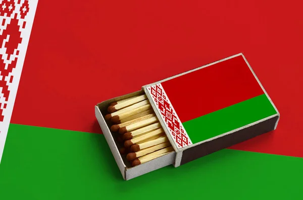 Belarus flag is shown in an open matchbox, which is filled with matches and lies on a large flag. — Stock Image Belarus Flag Shown Open Matchbox Which Filled Matches Lies Large Stock Image