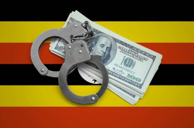 Uganda bayrağıyla kelepçe ve a bohça-in dolar. Ülkenin para birimi bozulması. Mali suçlar.