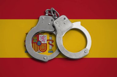 Spain flag  and police handcuffs. The concept of observance of the law in the country and protection from crime. clipart